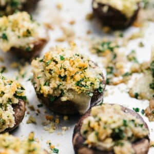 Mushrooms stuffed with Brie, breadcrumbs and parsley on a baking sheet pan.