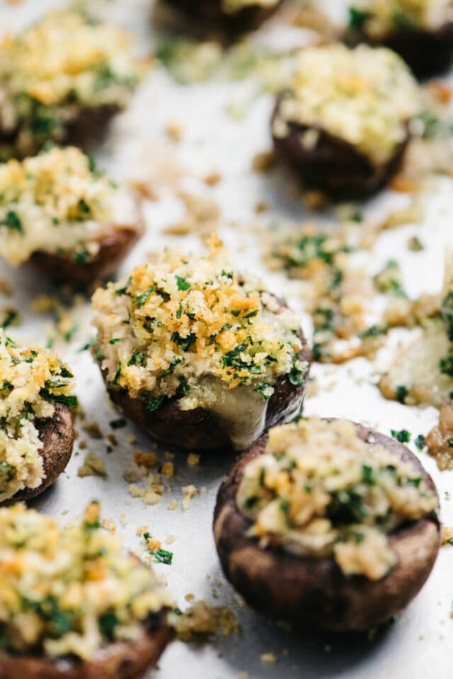Mushrooms stuffed with Brie, breadcrumbs and parsley on a baking sheet pan.