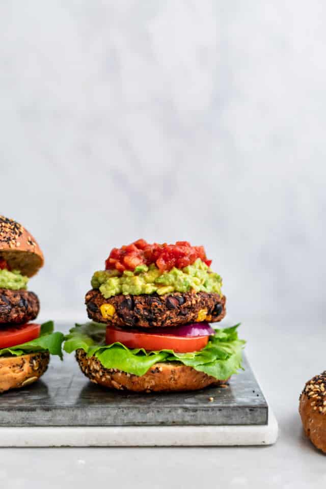 black bean veggie burger topped with lettuce, tomato, guacamole and salsa