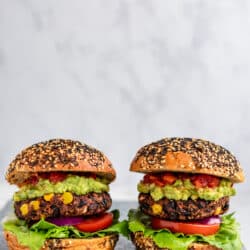 two of the best plant-based burgers topped with guacamole, tomato and lettuce