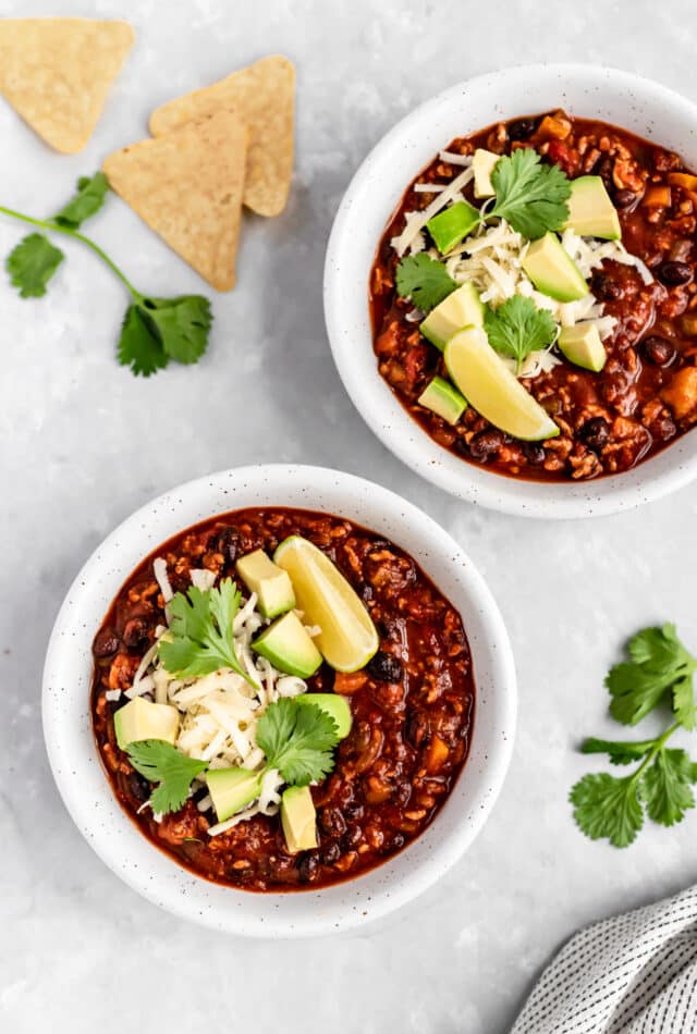 healthy turkey chili served in a white bowl with fresh cilantro and avocado