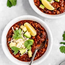turkey chili in a white bowl and topped with avocado slices, cheese and fresh cilantro