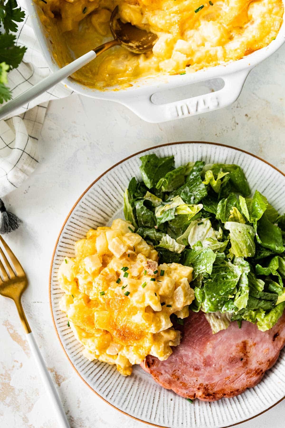 cheesy potato casserole served with a salad and ham