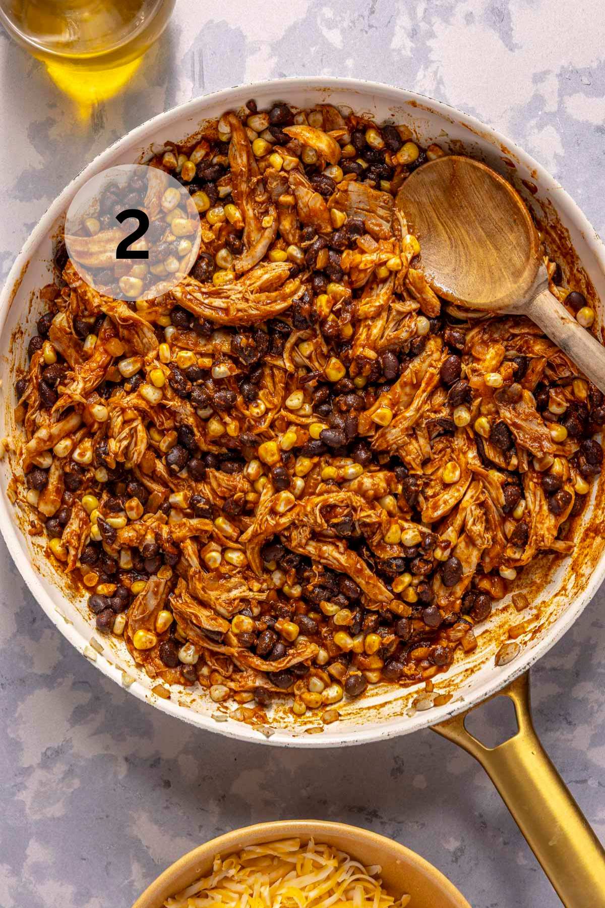 Stirring shredded chicken with black beans, corn and enchilada sauce in a skillet.
