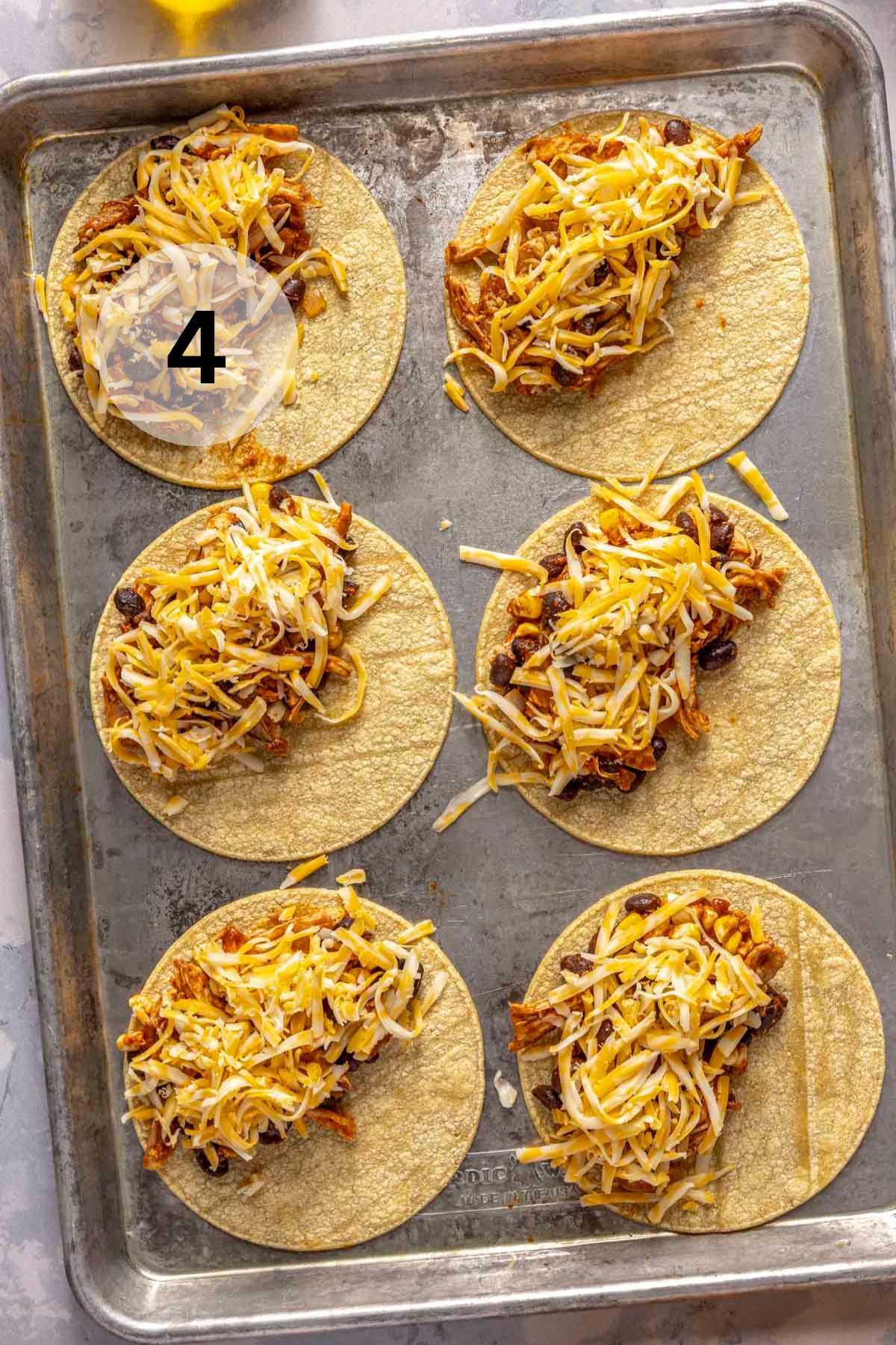 Adding filling to corn tortillas on a sheet pan.