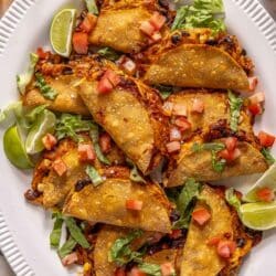 Crispy chicken tacos served on a white platter.