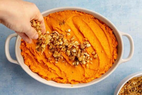 Hand sprinkle streusel topping over sweet potatoes.