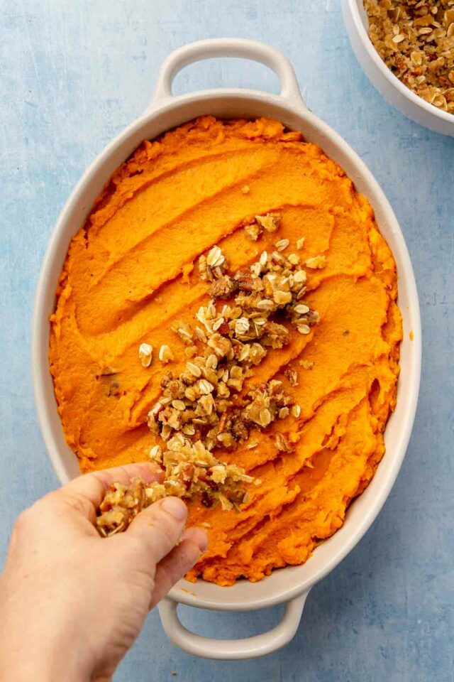 Hand sprinkle streusel topping over sweet potatoes.