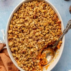 Sweet potato casserole in a white dish with a serving spoon.