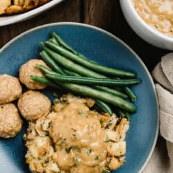 turkey dressing and gravy served with meatballs and green beans on a blue plate