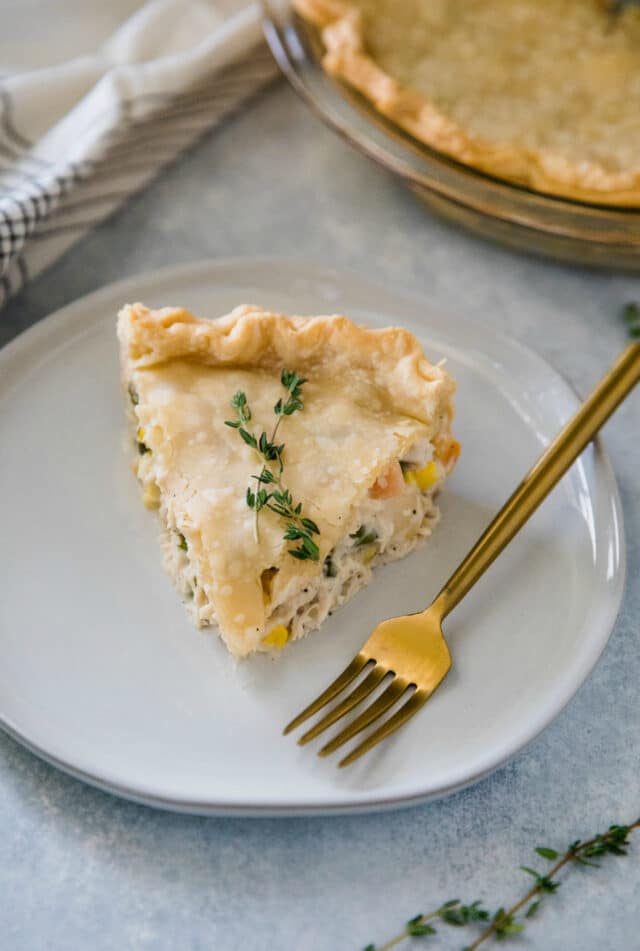 serving of chicken pot pie on a white plate with a gold fork