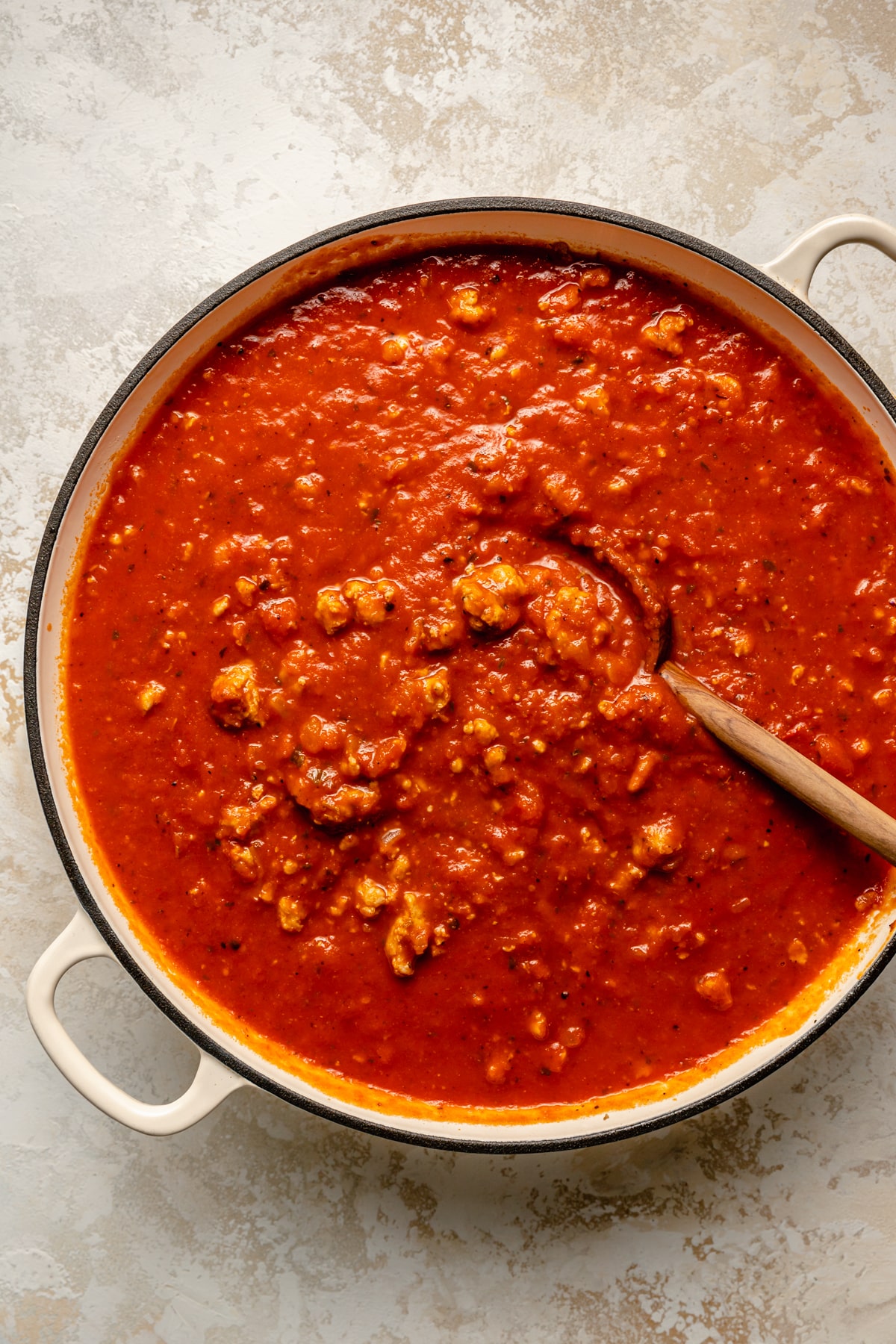 Adding marinara to meat in a large pot.