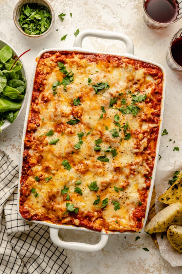 Baked pasta covered in cheese and garnished with fresh parsley.