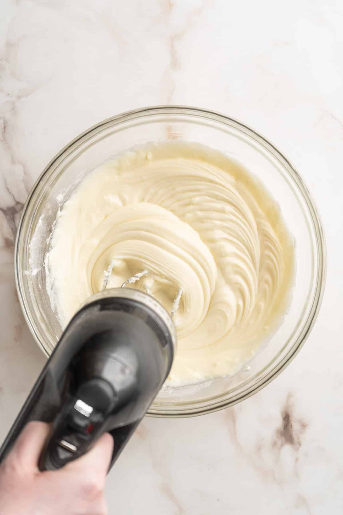 Using an electric mixer to mix cream cheese, flour and sugar.