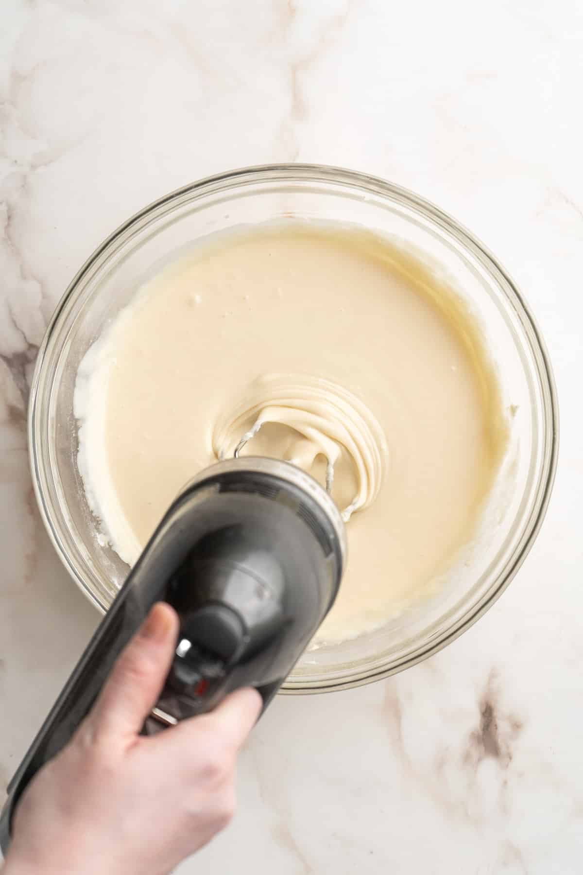 Using a handheld mixer to beat together the cream cheese filling.