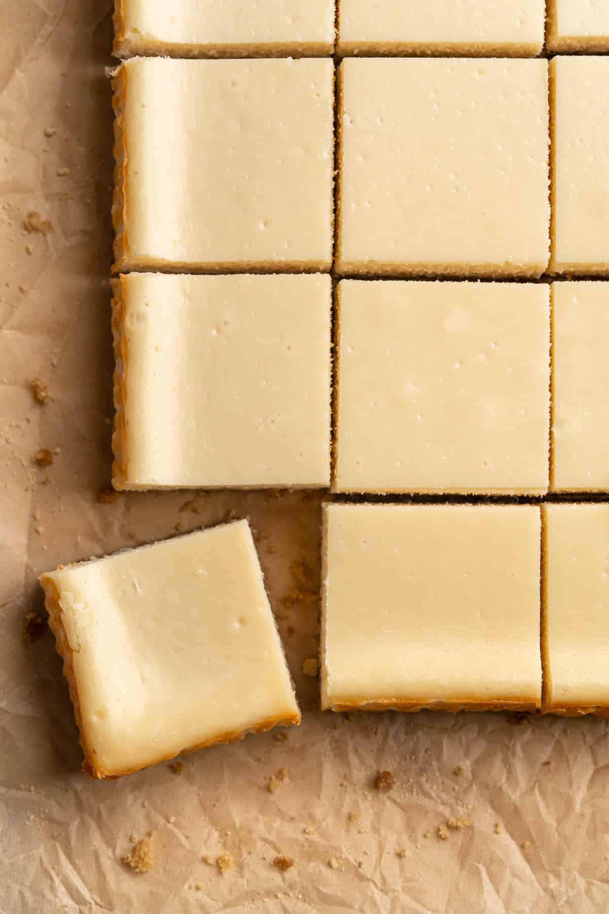 Cheesecake bars cut into squares on parchment paper.