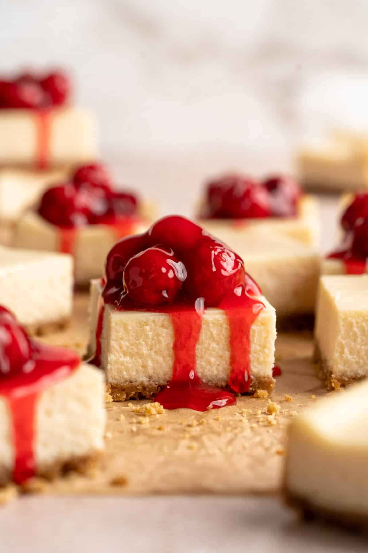 Cherry Cheesecake Bars with drizzling cherries coming down the sides of the bars.