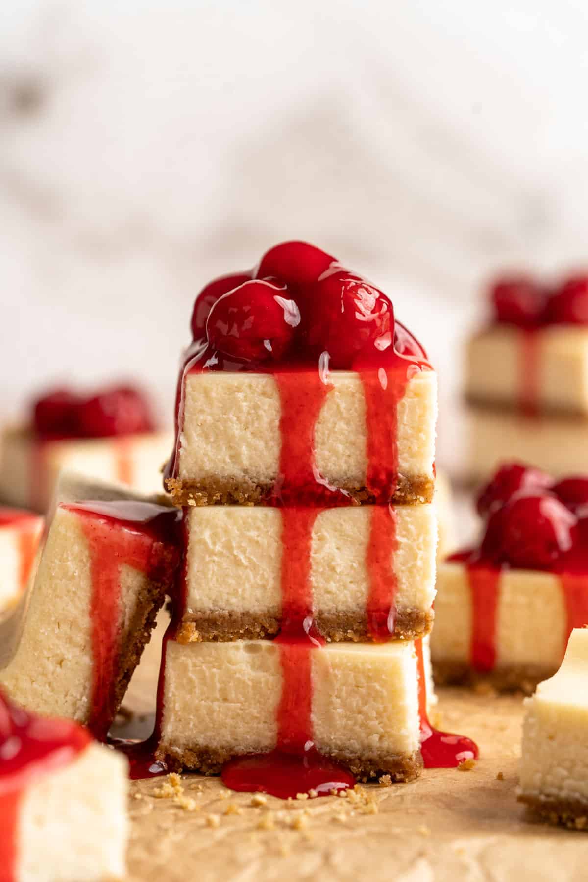 Three cheesecake bars staked and cherry pie filling over the top bar.