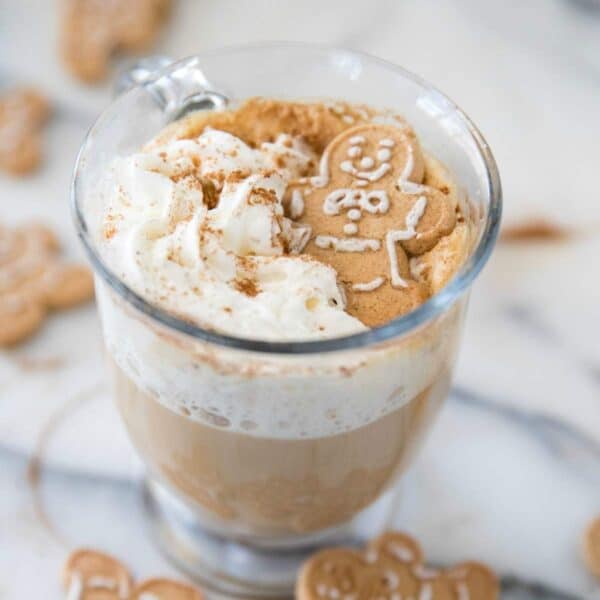 Coffee with whipped cream and a gingerbread man cookie.