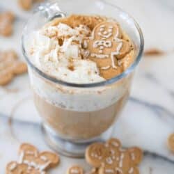 Coffee with whipped cream and a gingerbread man cookie.