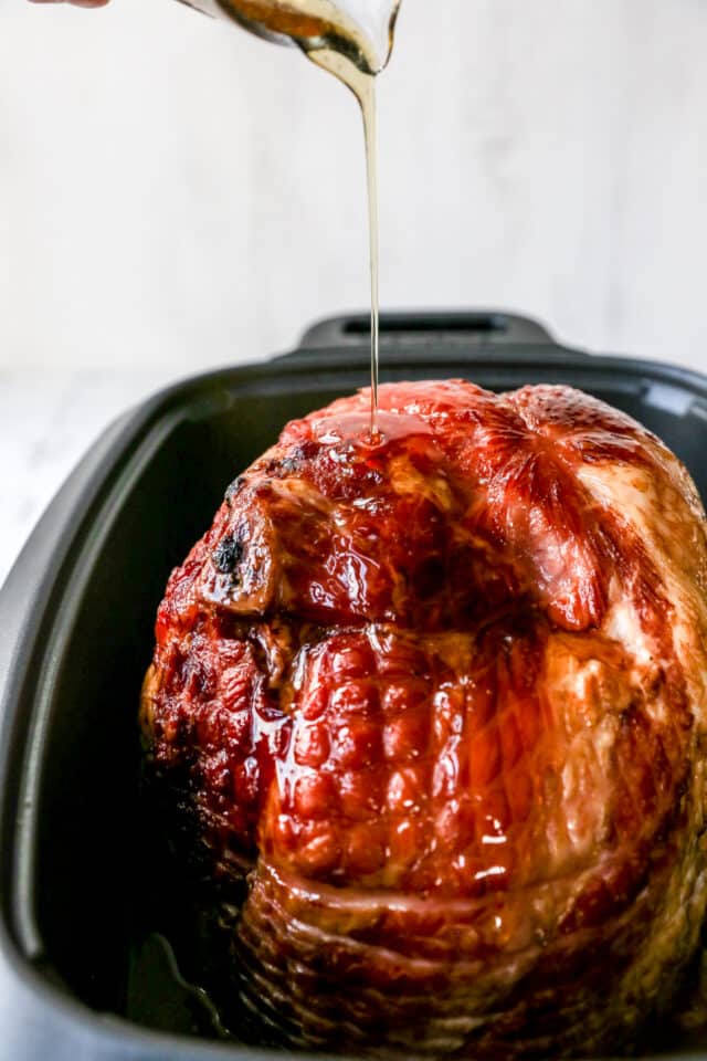 pouring honey over ham in a slow cooker