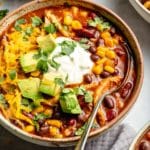 chicken taco soup topped with sour cream, cheese and avocado