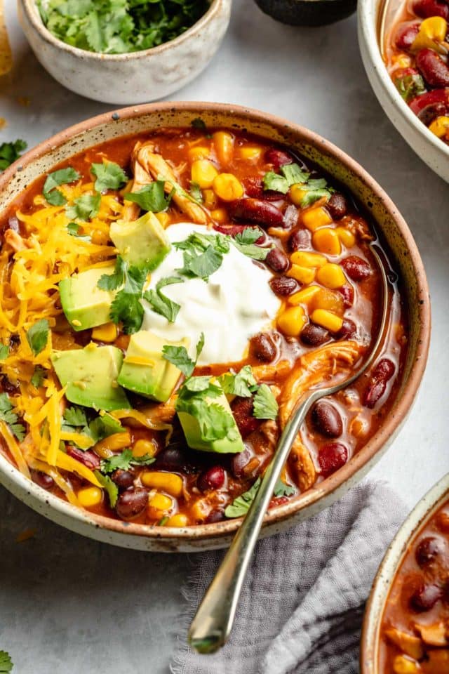 chicken taco soup topped with sour cream, cheese and avocado
