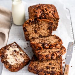 Chocolate Chip Banana Bread sliced on a bread board with a glass of milk