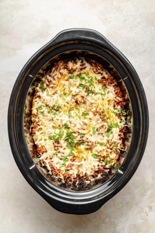 cooked crockpot lasagna topped with fresh parsley