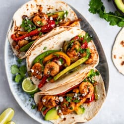 Shrimp Fajitas topped with avocado and serve with lime wedges