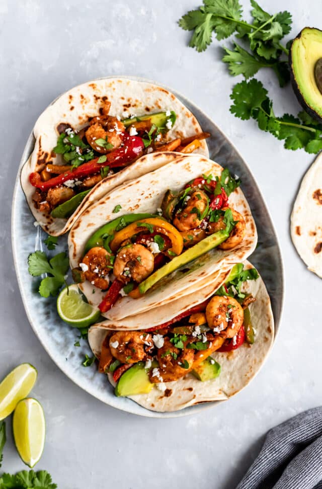 Shrimp Fajitas topped with avocado and serve with lime wedges