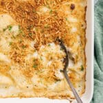 Cauliflower au gratin in a white casserole dish with serving spoon