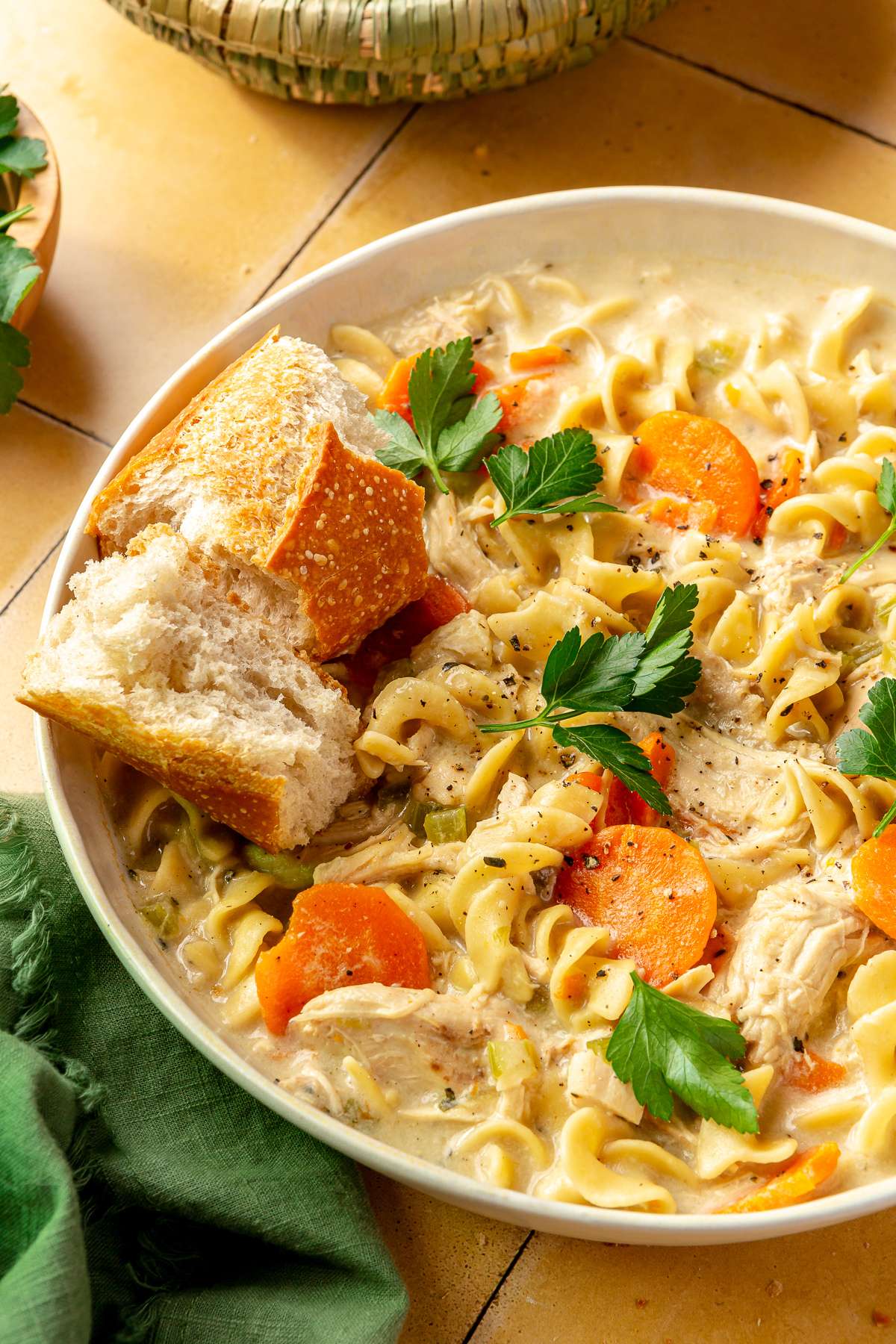 Soup with noodles, carrots and chicken served with bread.