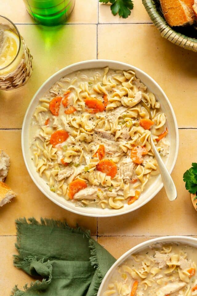 Creamy chicken noodle soup in a white bowl.