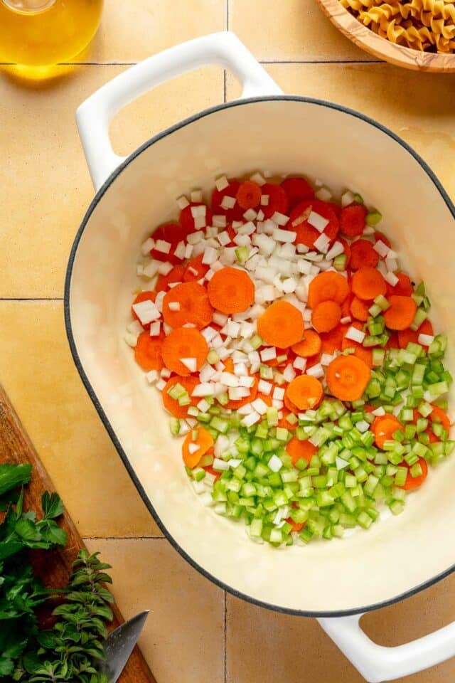 Sliced carrots, onion and diced celery sautéing in a pot.