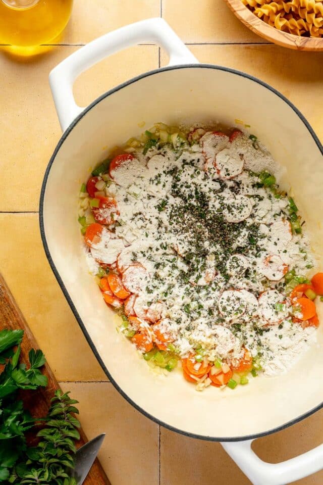 Add flour and seasoning to veggies cooking in a pot.