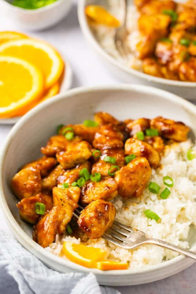 Orange chicken in a white bowl with rice.