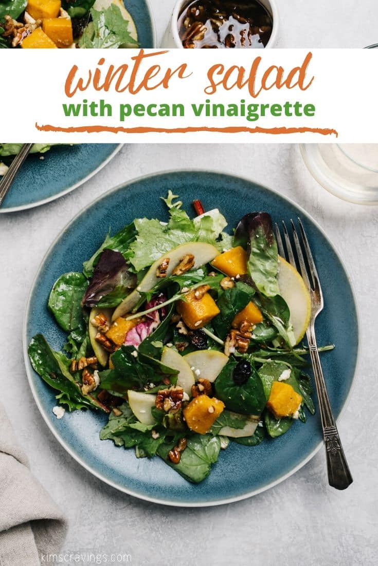 green salad with butternut squash and pecans served on a small blue plate