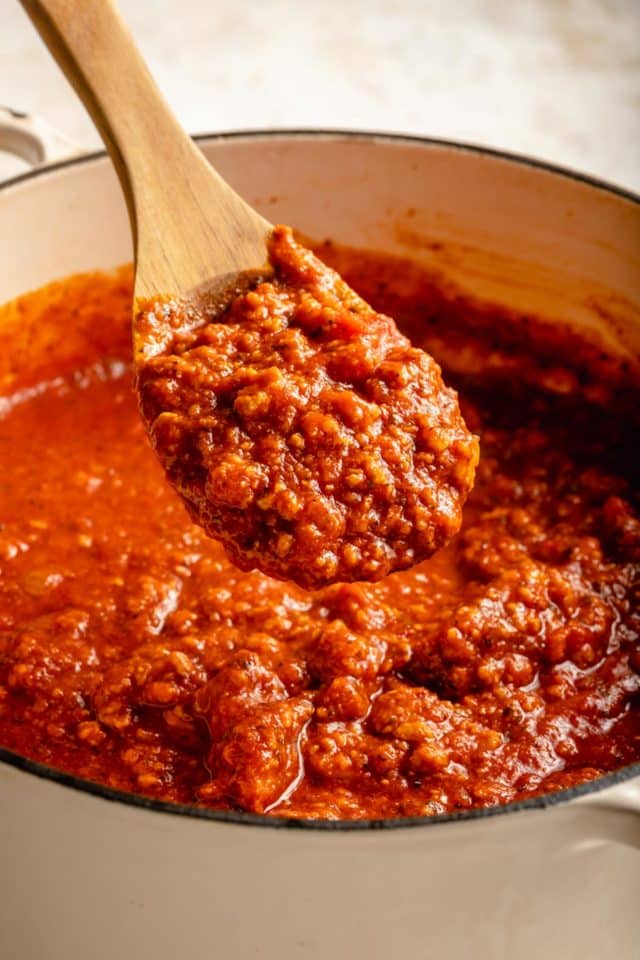 using a wooden spoon to serve meat sauce for pasta