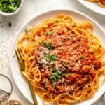 Spaghetti topped with a meat sauce on a white plate with a fork.