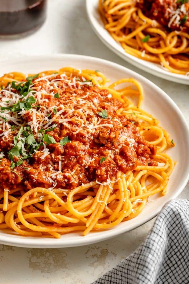 Plate of pasta topped with a meat sauce and Parmesan cheese.