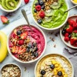 A green, berry and mango smoothie bowl topped with fruit and granola.