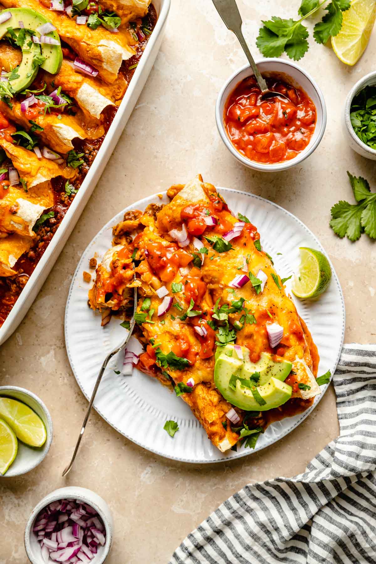 Two enchiladas on a white plate with a fork.