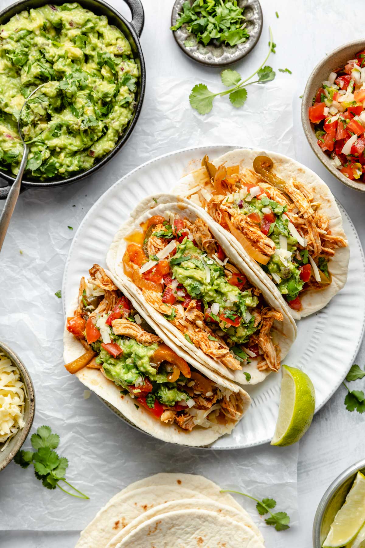 Three chicken fajitas on a plate with a lime wedge.