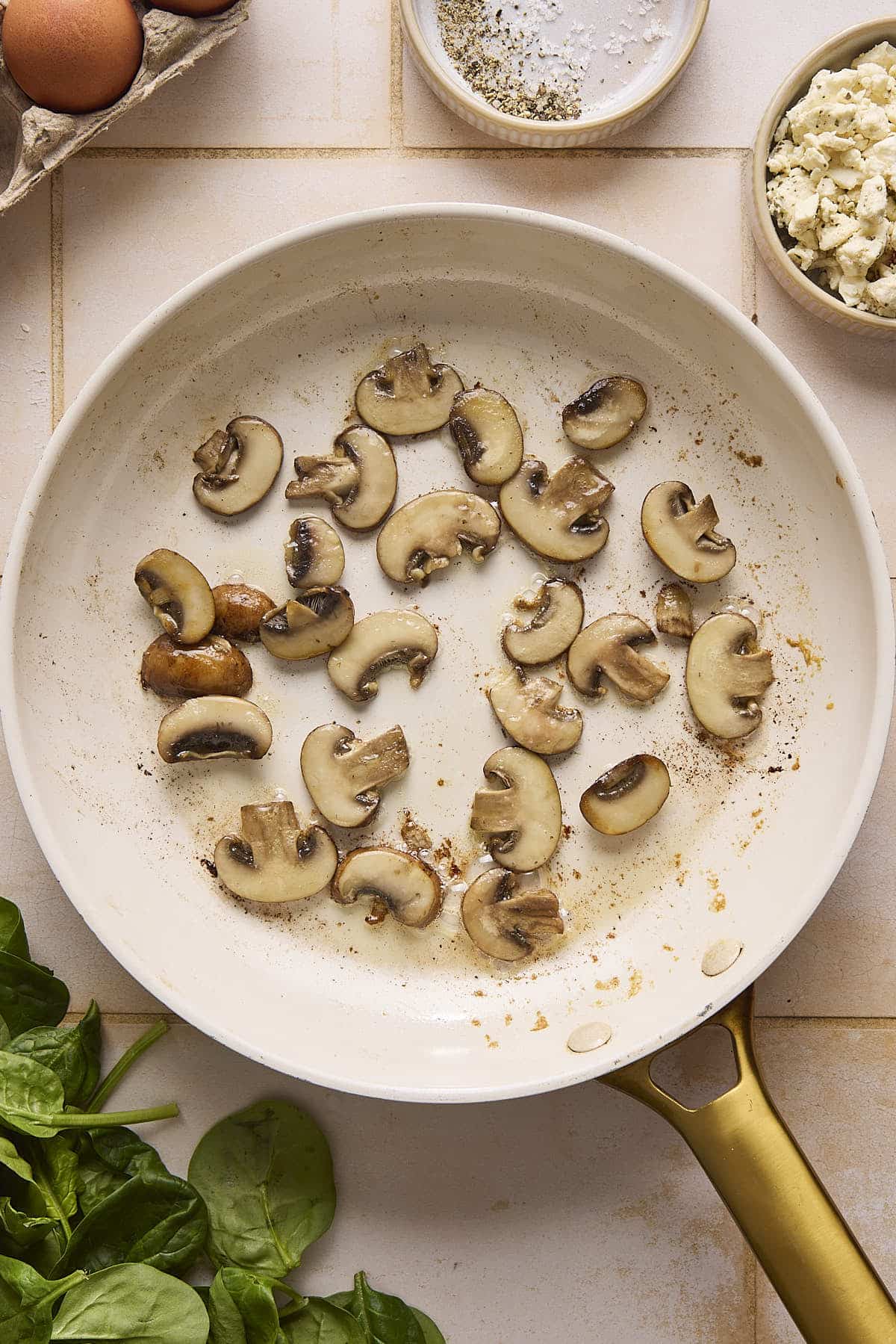 Mushrooms sautéing in a skillet.
