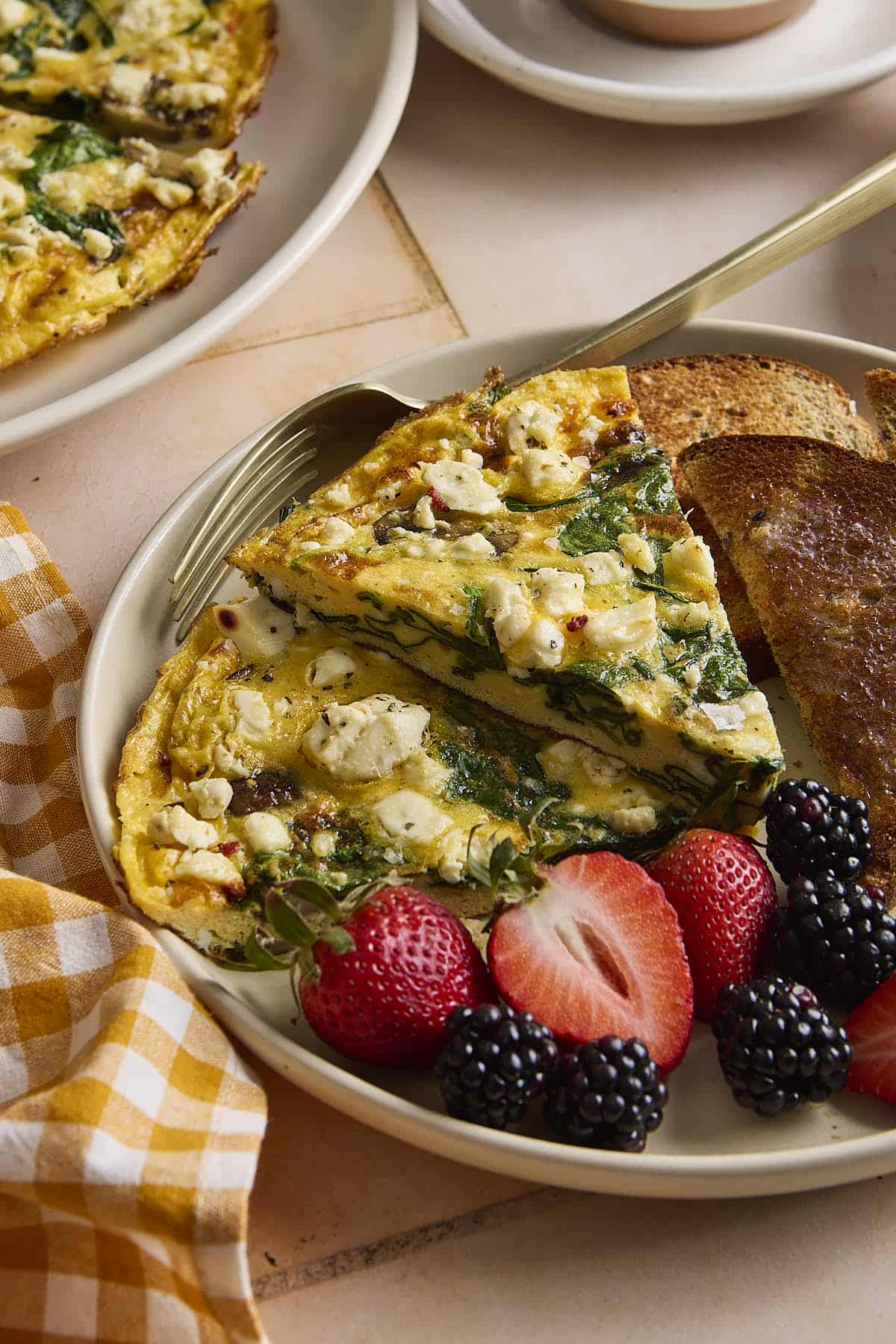Slices of frittata on a plate with berries and toast.