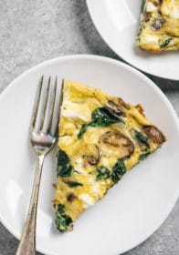 spinach and mushroom frittata on a white plate with a fork
