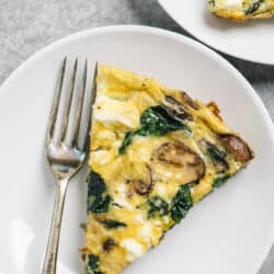 spinach and mushroom frittata on a white plate with a fork