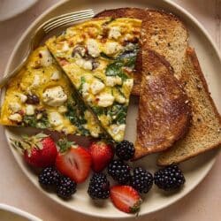 Slices of veggie frittata served with toast and fresh berries.