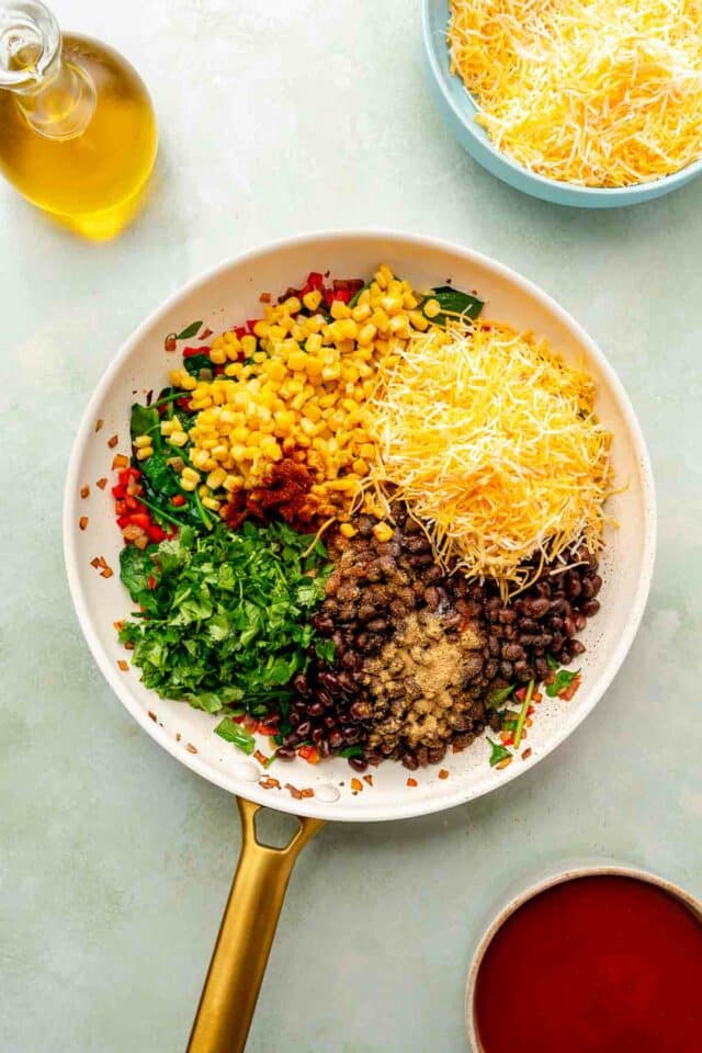 Adding shredded cheese, black beans, spices and corn to pan.